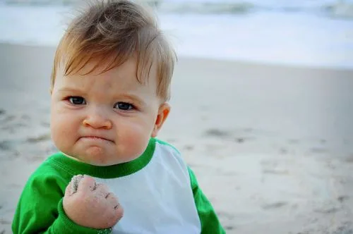 Success Kid meme showing a determined child at the beach with a curled hand.