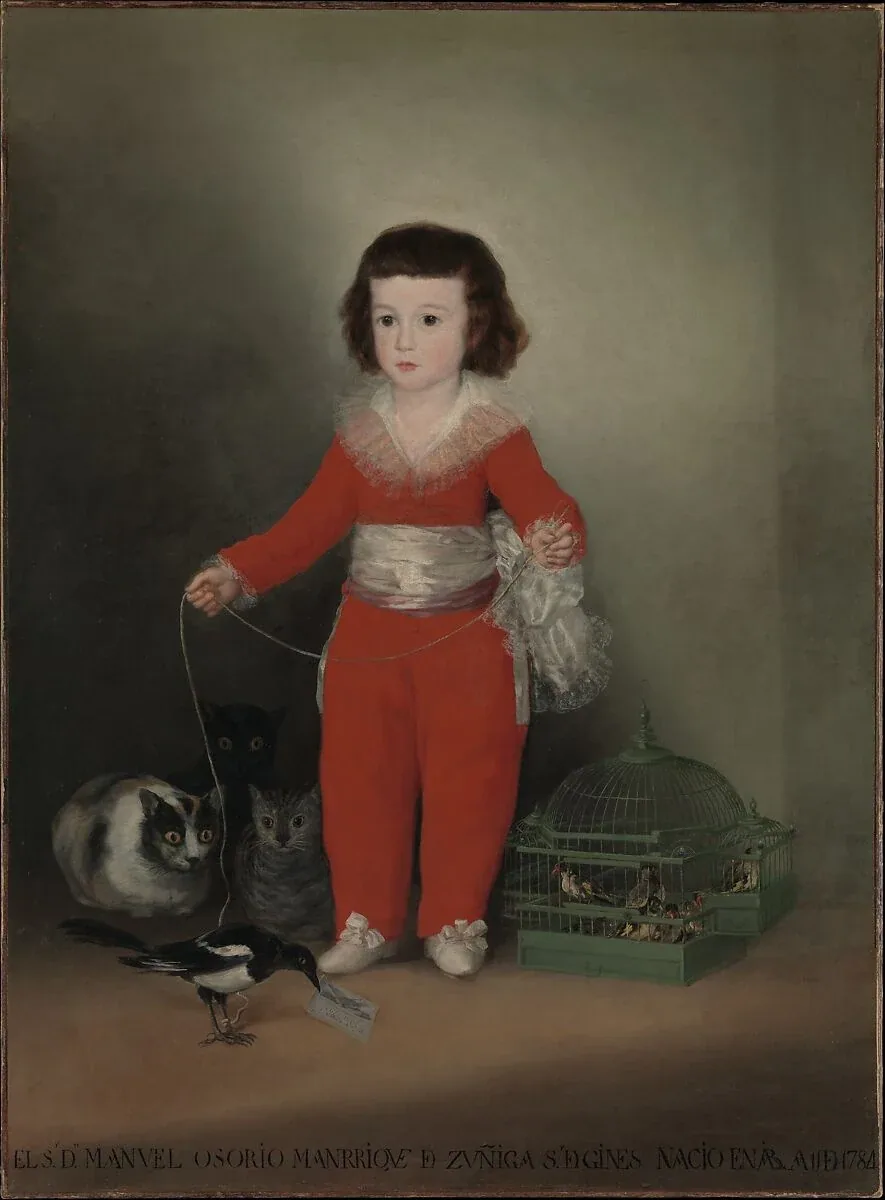 A boy in a bright red suit holds a magpie's string while three cats watch the bird from the shadows on the left.